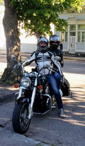 A man and a woman with helmets are sitting on a motorcycle.