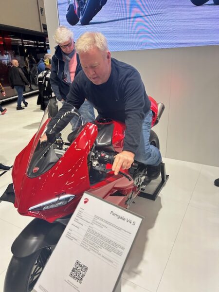 A man trying a red scooter.