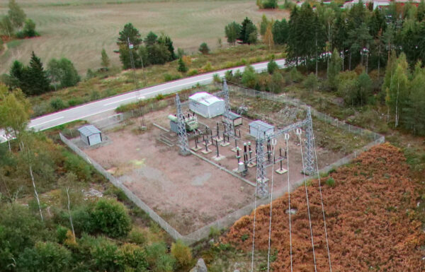 An outdoor power station surrounded by fields, trees and a road photographed from above.