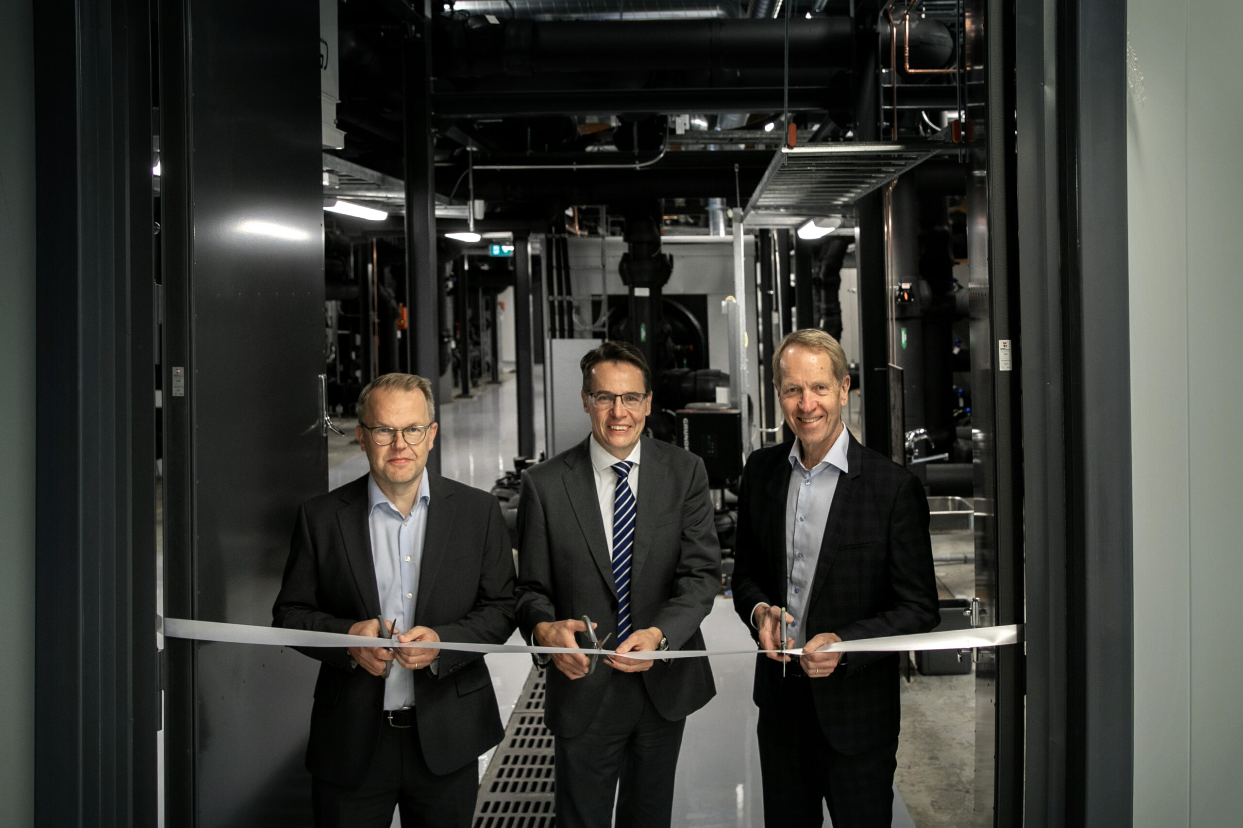 Three men in suits holding scissors, ready to cut a tape.